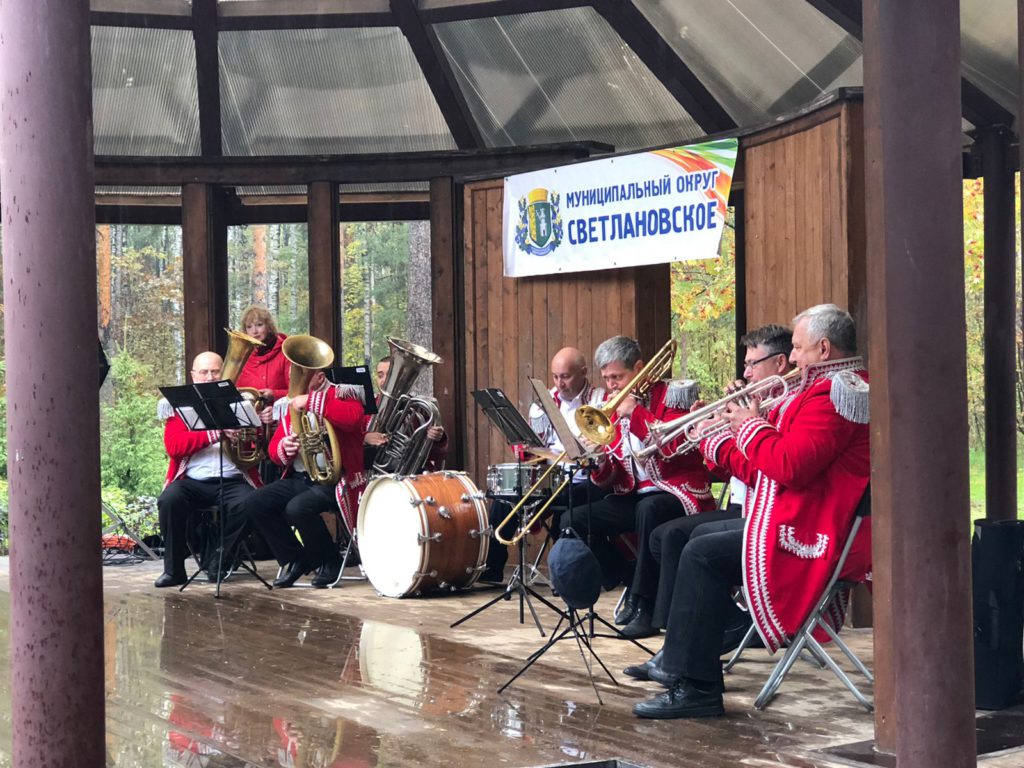 Музыканты духового оркестра играют на сцене в парке Сосновка 25.09.2021 в красных пиджаках 