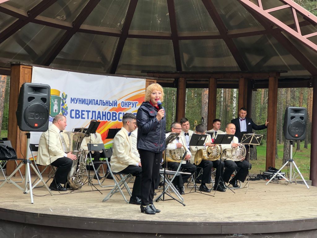 Музыканты оркестра играют на сцене в парке Сосновка