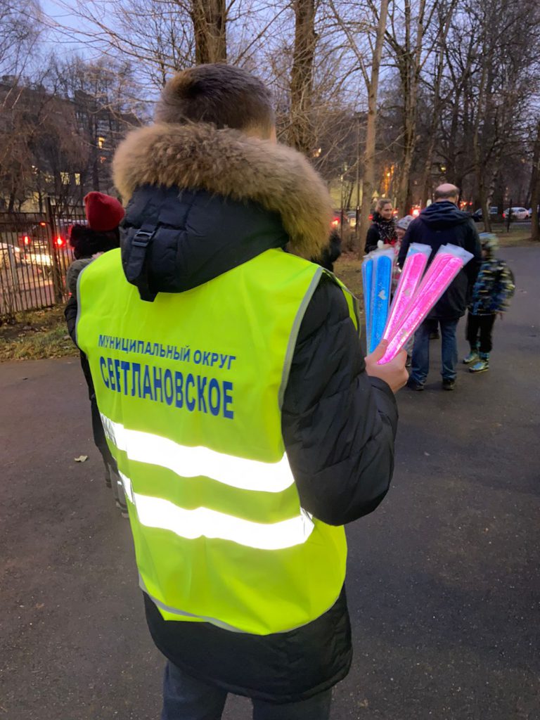 Сотрудник МО Светлановское держит в руках светоотражатели (браслеты).