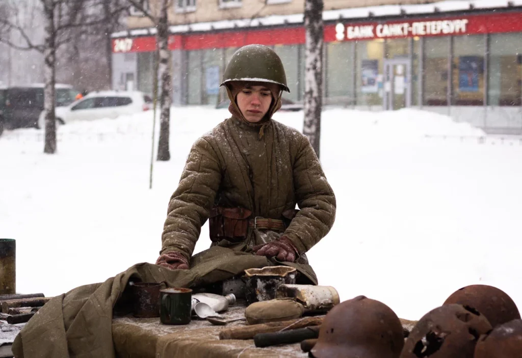 Экспозиция с предметами быта солдат времен Великой Отечественной войны 1941-1945 годов. Рядом стоит человек, одетый в форму солдата РККА. 