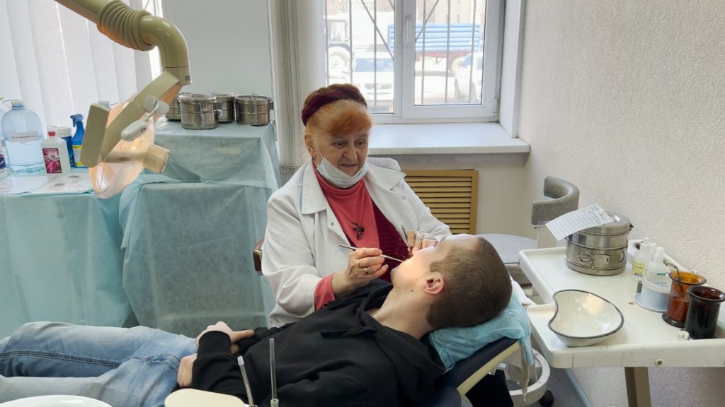 Призывник лежит на кушетке на приеме у стоматолога. 