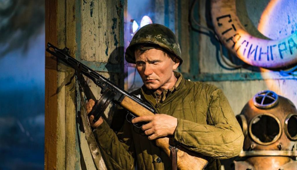 Восковая фигура в виде советского солдата в зеленой форме времен Великой Отечественной войны, на голове зеленая каска, в рукав ППШ.