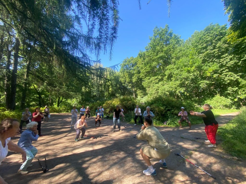 Пенсионеры МО Светлановское занимаются спортом в группе здоровья в парке. 